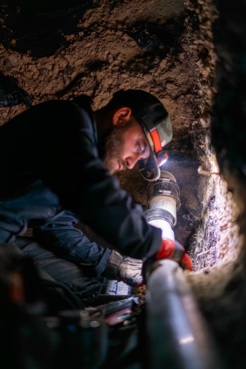 The Bearded Plumber technician inspecting plumbing beneath a foundation